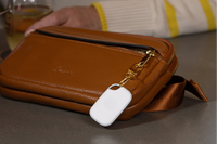 Image of a Tile Pro- White attached to a tan bag