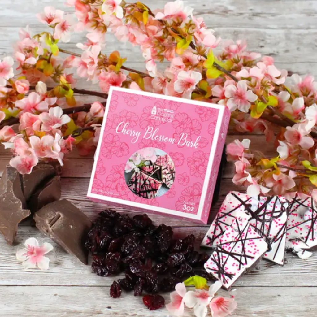 This candy is one of our favorite combinations cherries and chocolate! This bark features dark and white chocolaty layers infused with cherry oil and dried tart cherries. Throw on some pink sprinkles and dark drizzles you've got the perfect spring treat. This bark comes presented in a bright pink box with cherry blossom designs. 3oz box