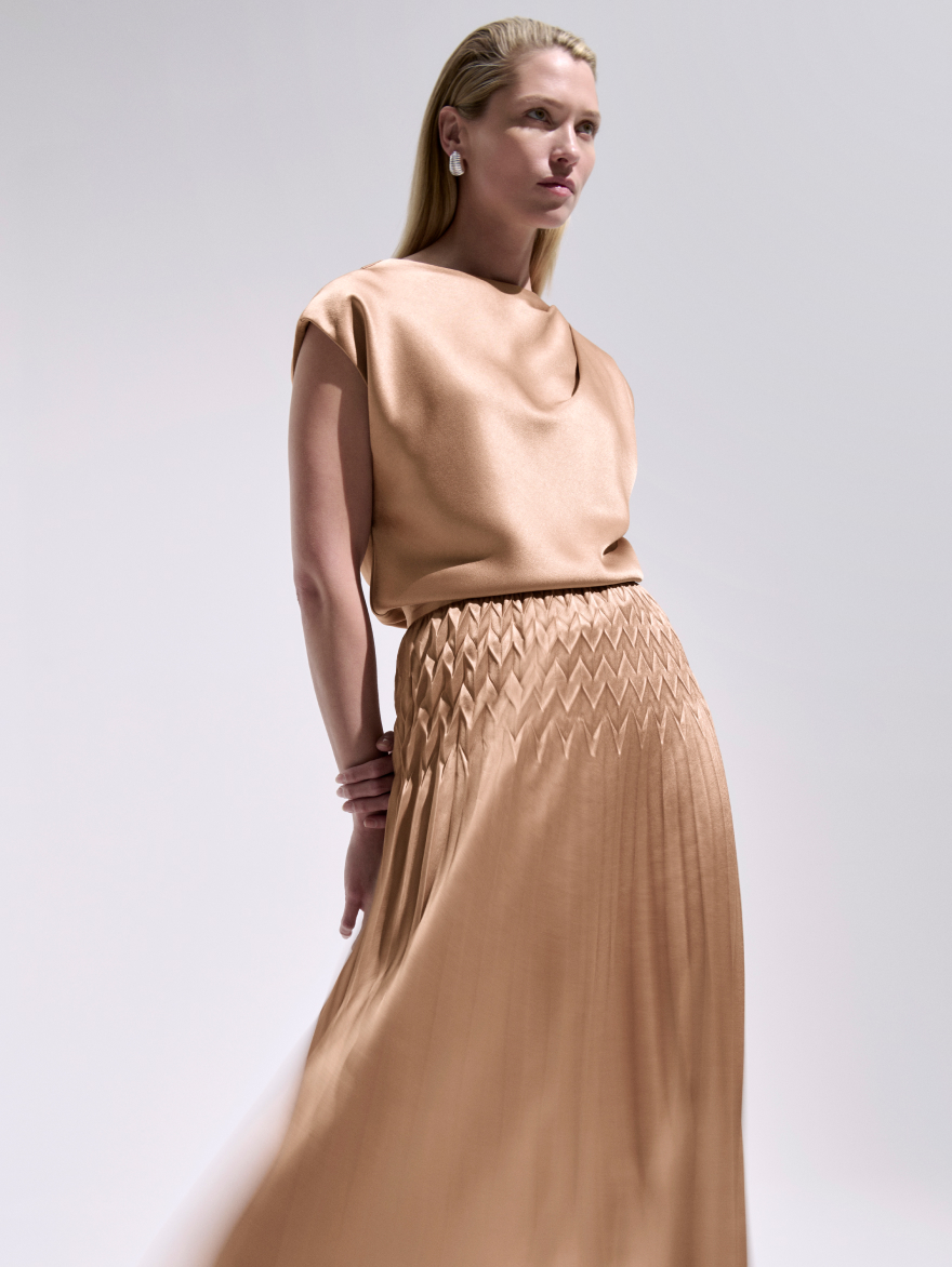 Model wearing camel Skye blouse and Venezia satin skirt