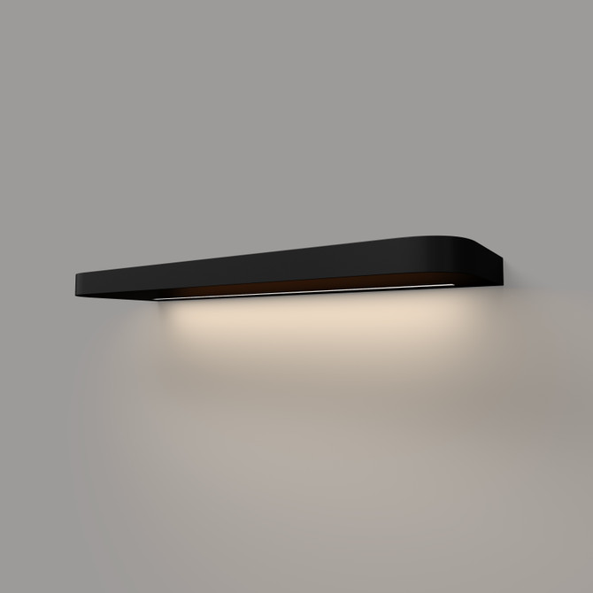 Angled view of a 1.625-inch thick black painted floating shelf with LED lighting and rounded front corners, mounted on a wall with a soft underglow.