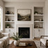 White painted maple alcove floating shelves installed in built-in living room niches on both sides of a fireplace.