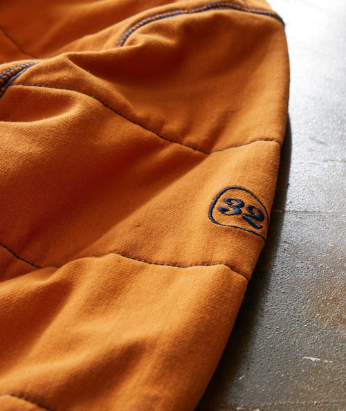 32 Bar Blues Perfect Way, close-up image of an orange fabric garment with embroidered black number 32 on the sleeve.