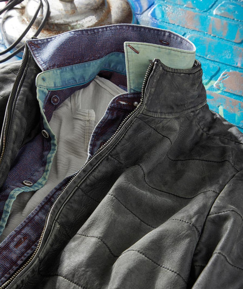 32 Bar Blues Double Lifetime, close-up of a black leather jacket with a layered interior showing a colorful patterned lining and a green shirt collar inside.