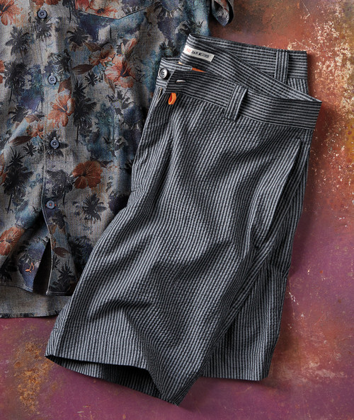 32 Bar Blues Side Tracked, image of black and gray striped dress pants placed on a textured surface with a floral patterned shirt partially visible beside them.