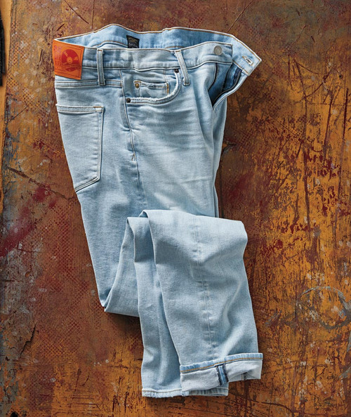 32 Bar Blues Take Me Back, light blue jeans with a classic fit and a vintage wash lay on a rustic wooden surface.