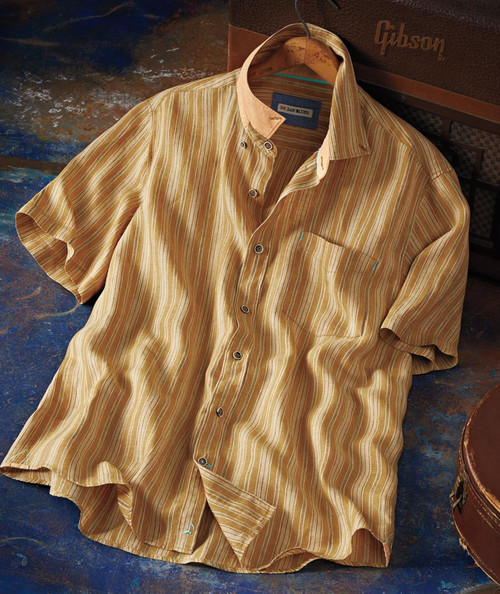 32 Bar Blues Do You Feel It?, a vintage striped short-sleeve button-up shirt with earthy tones and a contrasting collar, lying on a rustic blue surface.