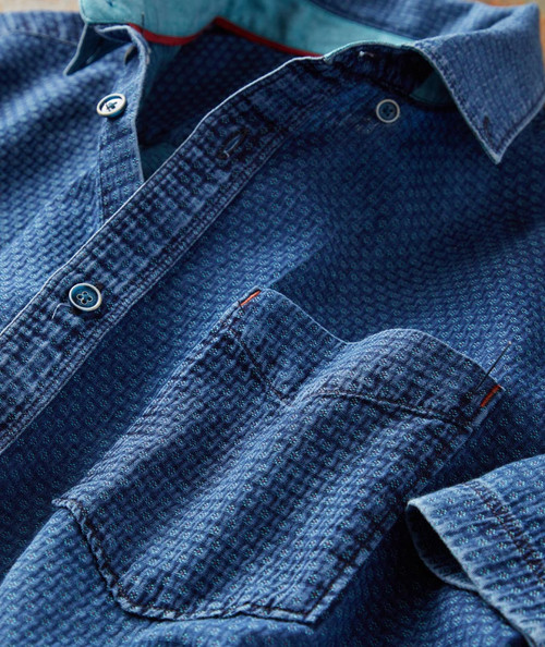 32 Bar Blues To The Point, close-up of a blue textured denim shirt with buttoned front and chest pocket.