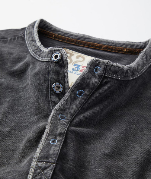 32 Bar Blues The Shake, close-up of a black casual shirt with a henley neckline and blue embroidered buttons.