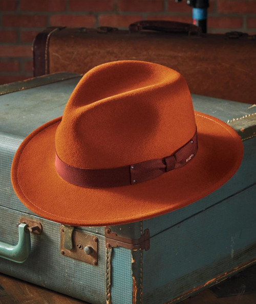 32 Bar Blues Verve, stylish orange fedora hat with a dark band resting on an antique teal suitcase.