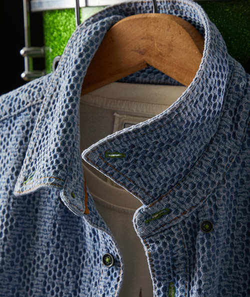 32 Bar Blues Jumpy Blues, close-up of a textured blue patterned fabric shirt hanging on a wooden hanger.