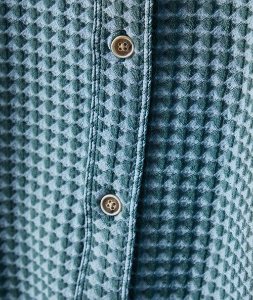 32 Bar Blues Diamond Mine, close-up view of the button placket on a textured woven shirt with a diamond pattern and two beige buttons.
