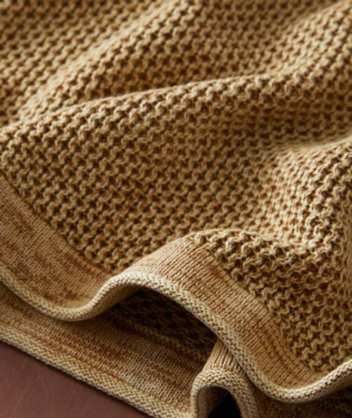 32 Bar Blues Butterscotch, close-up of a textured knitted fabric in butterscotch color with a detailed pattern and fold showing the material's softness and warmth.