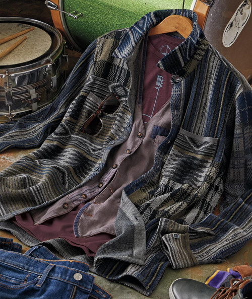 32 Bar Blues Spirits Rise, a casual music-inspired outfit with a patterned shirt, sunglasses, and denim jeans, placed near drums and musical accessories.