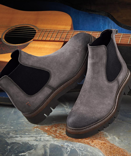 32 Bar Blues Wide Open Road, gray suede men's ankle boots with black elastic side panels and rugged rubber sole placed in front of an acoustic guitar.