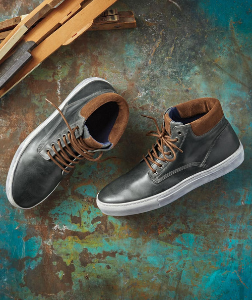 32 Bar Blues The Oneness Of Two, pair of stylish black leather sneakers with brown accents and white soles, displayed on a colorful, textured floor.