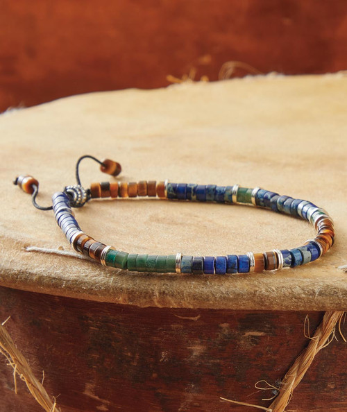 32 Bar Blues Use What You Got beaded necklace, handcrafted jewelry featuring small cylindrical beads in blue, green, and brown colors with silver accents on a wooden surface.