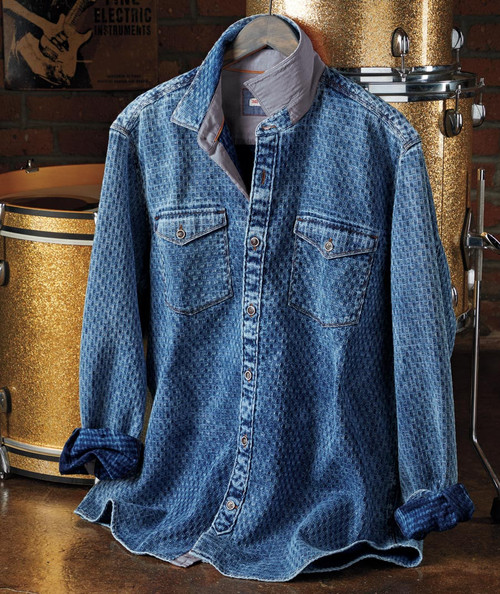 32 Bar Blues Blue Blazes Denim Shirt, an image of a vintage-style blue denim shirt with a pattern, featuring front chest pockets, metal buttons, and rolled-up sleeves, displayed against musical instruments background.