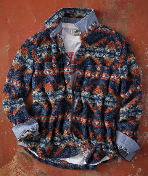 32 Bar Blues Dancing In The Canyon, cozy patterned fleece jacket with navy, rust, and cream geometric design, layered over a white graphic t-shirt, on a rustic red floor.