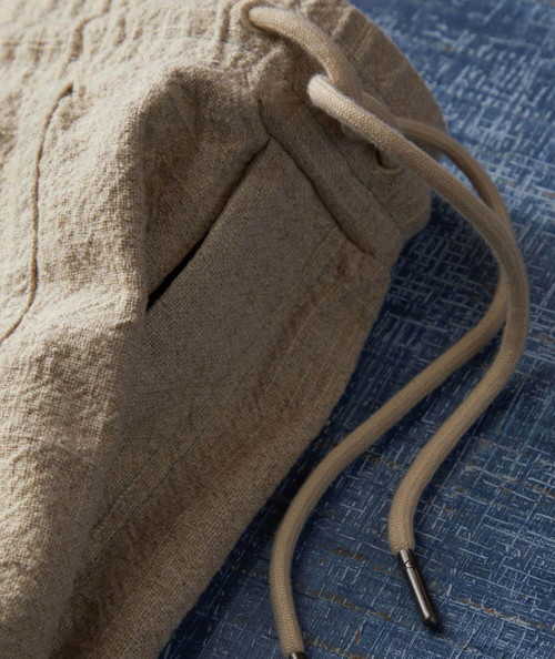 32 Bar Blues Drifter, beige fabric bag with drawstring closure and textured material on blue patterned surface.