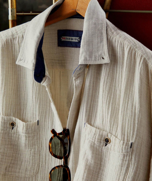 32 Bar Blues The Opener, beige striped casual shirt with front pockets and tortoise shell sunglasses hanging from it.