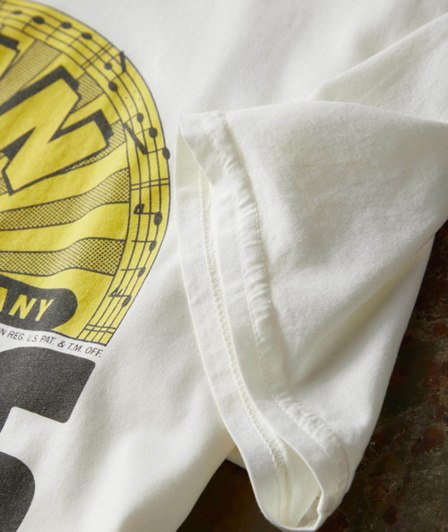 32 Bar Blues Let's Begin, close-up of the white fabric and yellow logo design on the T-shirt.