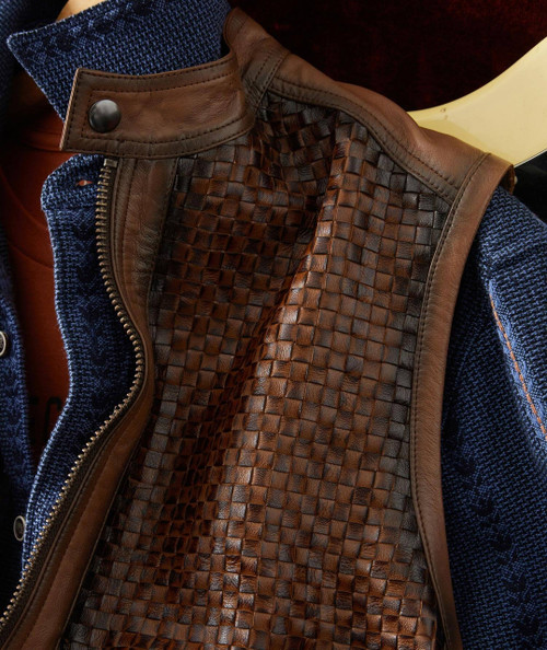 32 Bar Blues Hello Number One, a close-up image of a brown woven leather vest layered over a blue textured sweater.