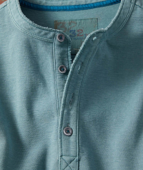 32 Bar Blues Bassism, close-up of teal textured button-up shirt with top buttons, collar detail, and visible label.