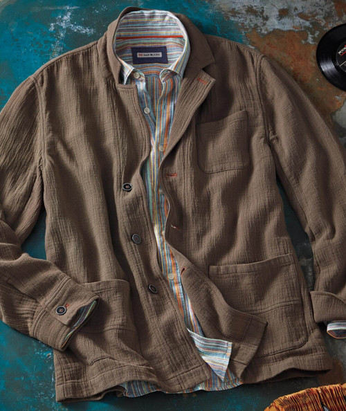 32 Bar Blues Everything Must Change, casual brown textured blazer with a colorful striped shirt underneath, laid out on a rustic surface with a vinyl record nearby.