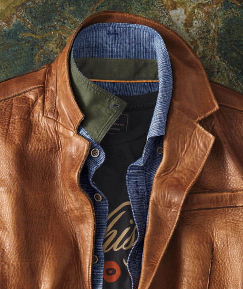 32 Bar Blues Flyjack, a brown leather jacket with a layered collar showing a blue and black inner lining and a black shirt underneath.