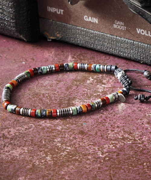 32 Bar Blues In That Order, colorful beaded necklace lying on a textured pink surface with an amplifier in the background.