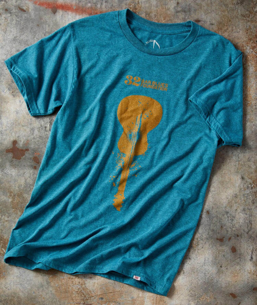 32 Bar Blues This Old Guitar T-Shirt, a teal-colored fabric T-shirt featuring a gold silhouette of a guitar with paint splashes and text design.