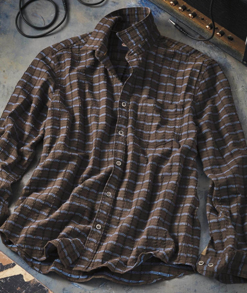 Wavy Gravy, brown and black plaid flannel shirt with button-up front and collar, laid flat on a concrete surface.