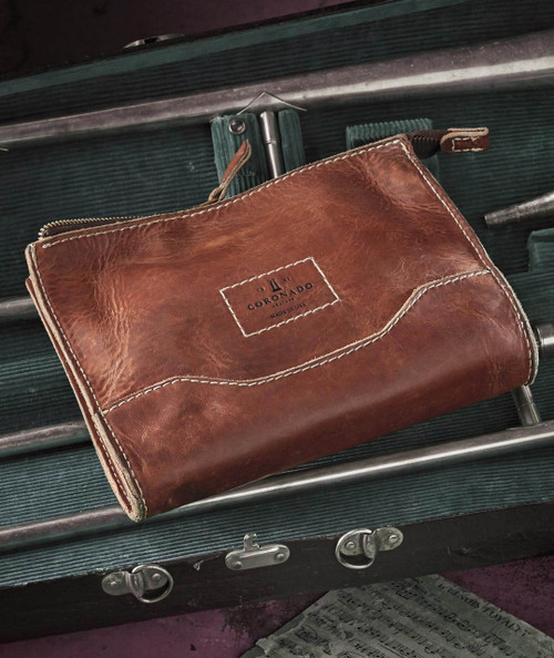 Stash Dash, leather zippered pouch or bag with visible stitching and logo, on green surface with metal handles and locks