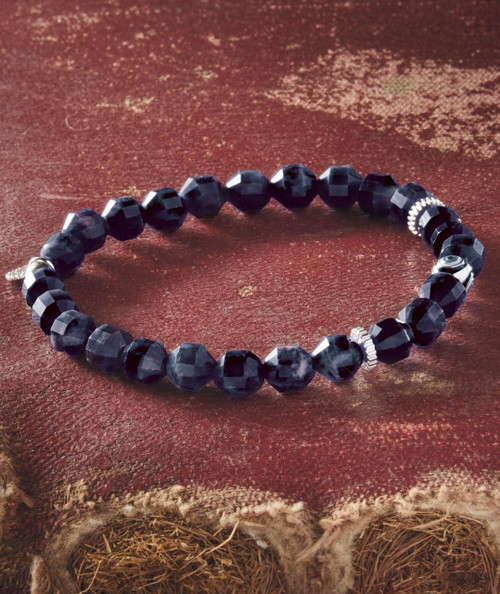 Roll Me Up, black faceted bead bracelet with metallic accents on a textured surface.