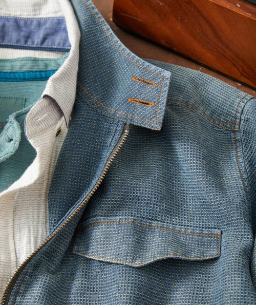 Fast Ride, close-up of a stylish denim jacket showing detailed fabric texture and orange stitching on the collar and pocket.