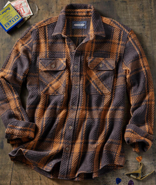 Boom Boom, plaid brown and black flannel shirt with chest pockets on a rustic wooden surface