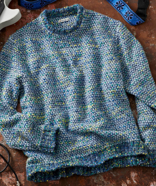 Hub's Nub, textured multicolor knitted sweater with speckled yarn in blue, yellow, and green on a brown surface.