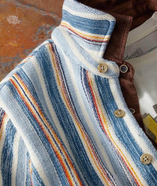Double Play, close-up image of a striped knit shirt with beige buttons and a maroon jacket partially visible.