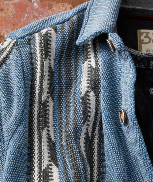 Let Me Be Your Side Track, close-up of a textured blue patterned fabric shirt or jacket with metallic buttons.