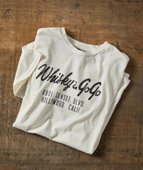 Sunrise On Sunset T-shirt, white T-shirt with black text design featuring the words 'Whisky & Co' and the address '8901 Sunset Blvd, Hollywood, Calif' on a wooden surface.