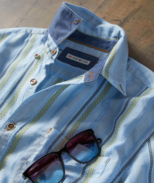 Buzzy, casual men's denim shirt with embroidered details and sunglasses on a wooden surface.