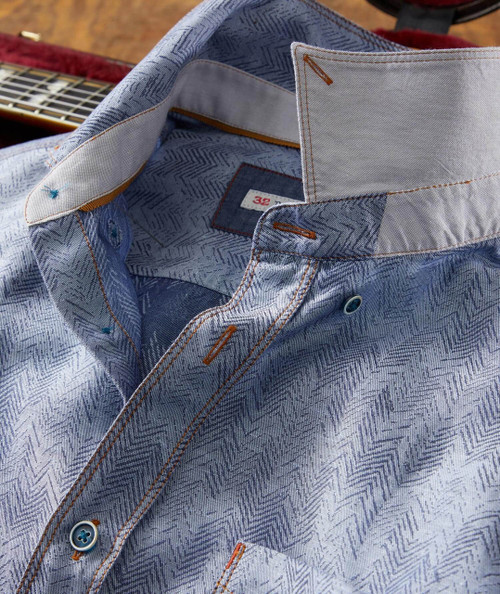 Bye Ya shirt, close-up of a light blue men's formal shirt with a subtle zigzag pattern, orange-brown stitching, and a partially open collar.
