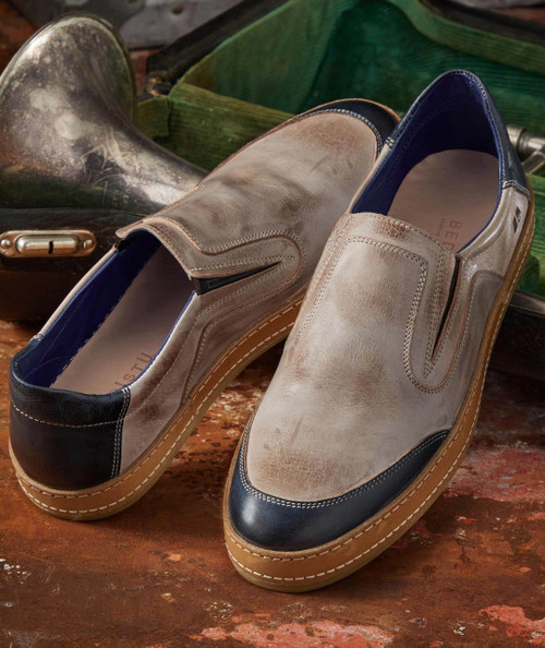 Split Kick, a pair of beige and black slip-on shoes with a casual design and thick sole, displayed on a rustic wooden surface.