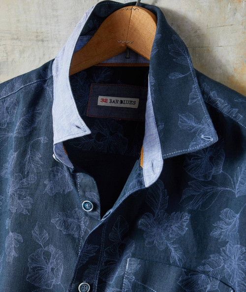 Moonshiner Men's Casual Button-Down Shirt featuring a dark blue floral pattern, collared design, and front buttons, hanging on a wooden hanger.
