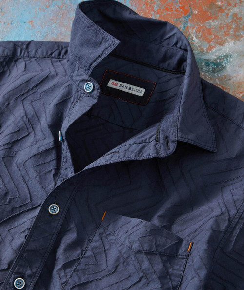 Boomerang, blue stylish men's shirt with a geometric pattern and button-down collar laying flat on a textured surface.