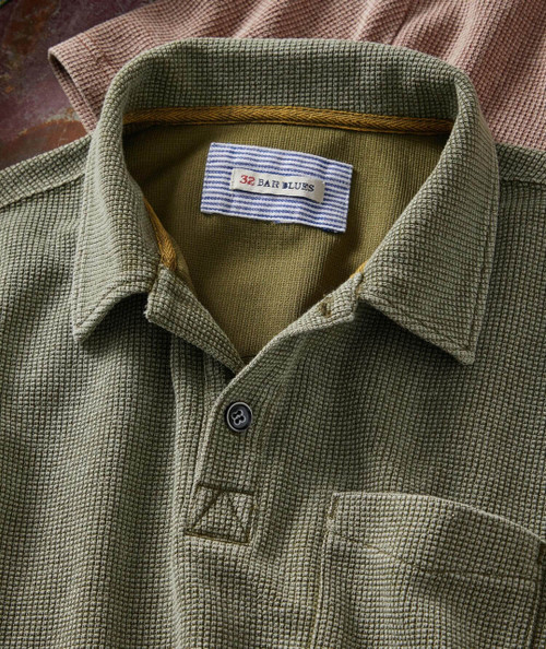 The Easy Winner, close-up of a green textured button-up shirt with a patterned collar and a brand label '32 BAR BLUES' inside the collar.