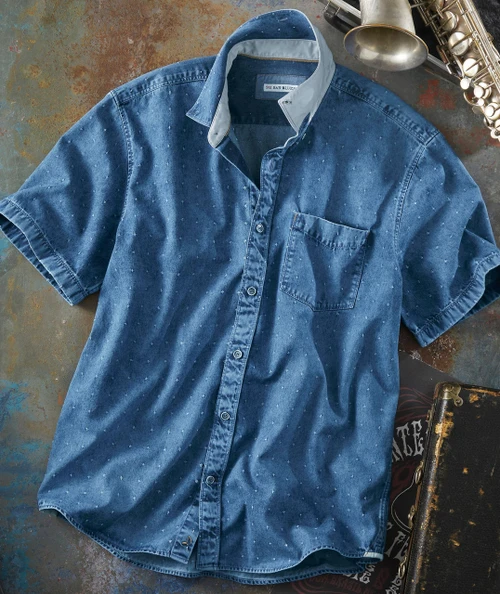 Point Made men's short-sleeve denim shirt with small white pattern, button-up front, and chest pocket, laid flat on rustic surface with saxophone and record case around it.