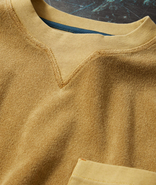 Steady Gettin' It, a close-up image of a fashionably designed tan sweatshirt with a V-shaped neckline and textured fabric, laid on a dark background.