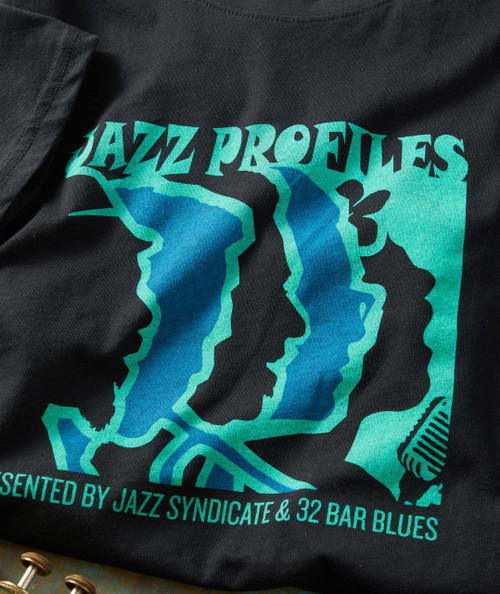 The Show Must Go On T-shirt, black fabric T-shirt featuring a colorful graphic design with faces and text about jazz music.