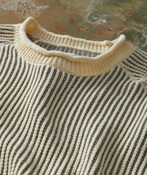 Groove's Groove, close-up of a striped knit sweater with a cream-colored collar on a textured surface.